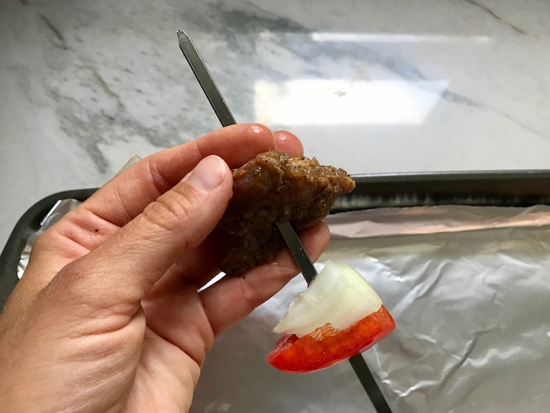 Putting skewer through beef, onion and red pepper for Garlic Steak Kabobs. #beefkabobs #steakkabobs