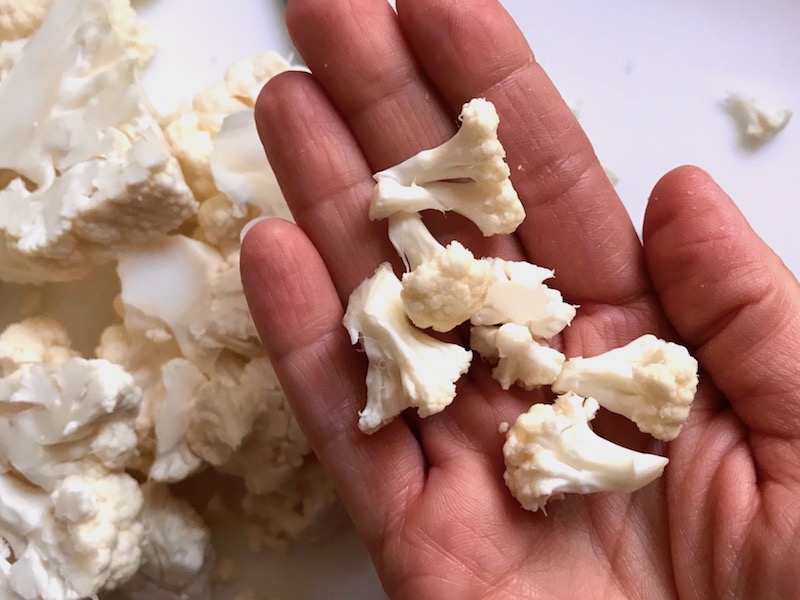 Cauliflower florets in hand for Quinoa Black Bean Burritos. Packed with protein and fiber, but also cheese, tomato, cilantro, and sour cream! The vegetarian 'meat' is taco-seasoned quinoa, black beans, and cauliflower.