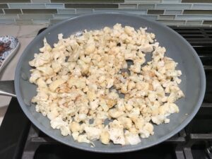 Cauliflower florets in pan for Quinoa Black Bean Burritos. Packed with protein and fiber, but also cheese, tomato, cilantro, and sour cream! The vegetarian 'meat' is taco-seasoned quinoa, black beans, and cauliflower.