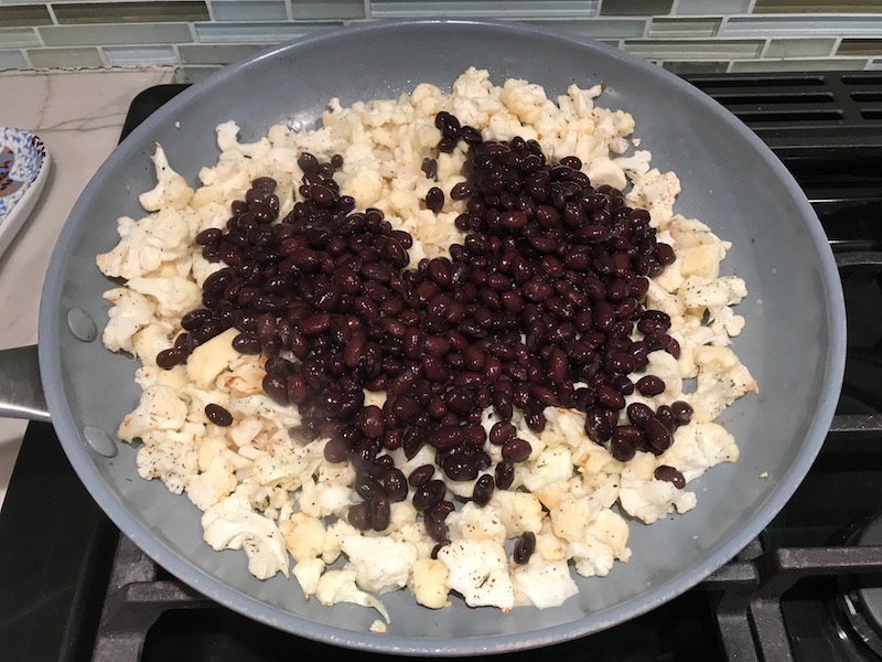 Black beans and Cauliflower florets in pan for Quinoa Black Bean Burritos. Packed with protein and fiber, but also cheese, tomato, cilantro, and sour cream! The vegetarian 'meat' is taco-seasoned quinoa, black beans, and cauliflower.