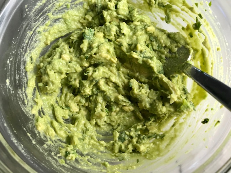 Mixed Guacamole for a Taco Chicken Burger recipe. The burger has smokey taco seasonings, cilantro, and scallions. Then on top are melty cheese, guacamole, lettuce, tomato, and chipotle mayonnaise!
