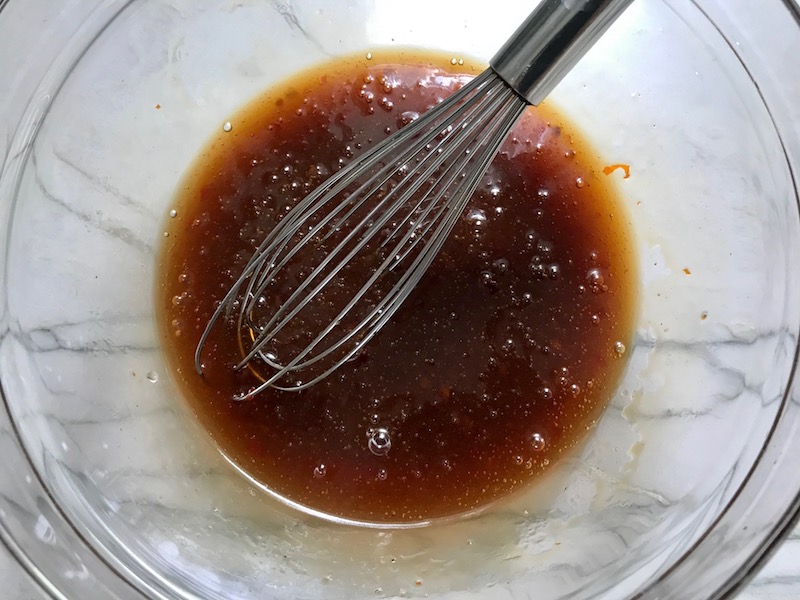 Sweet and Sour sauce with whisk in bowl for Sweet and Sour sauce Chicken Kabobs with pineapple, onion, and red pepper.