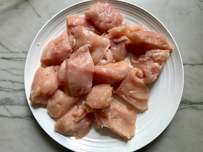 Raw Chicken breast kabob pieces on a plate for Sweet and Sour sauce Chicken Kabobs with pineapple, onion, and red pepper.