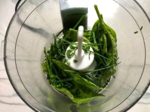 Basil and chives in food processor for Green Rice Recipe. It takes white rice from plain to amazing with just 5 ingredients. Filled with herbs and spinach, it has the perfect herby flavor.