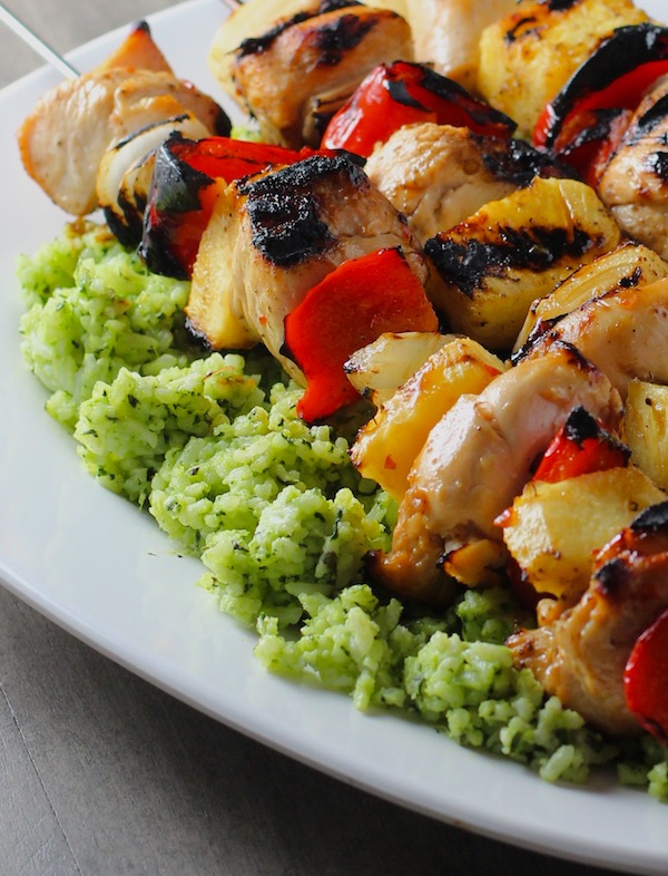 Green Rice on platter with chicken kabobs on top. This Recipe takes white rice from plain to amazing with just 5 ingredients. Filled with herbs and spinach, it has the perfect herby flavor.