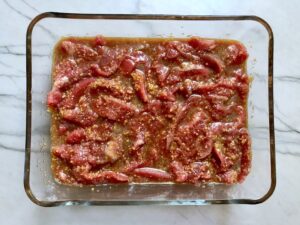 Raw flank steak in marinade in dish for Korean Beef Tacos with flavorful Korean beef, crunchy Sesame Cabbage Slaw and a creamy, cool, Cilantro Lime Sriracha sauce!