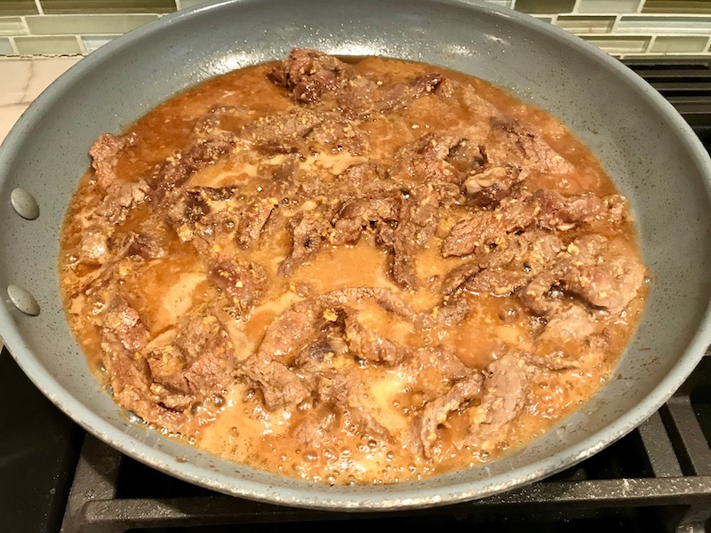 Korean Flank steak cooking in pan for Korean Beef Tacos with flavorful Korean beef, crunchy Sesame Cabbage Slaw and a creamy, cool, Cilantro Lime Sriracha sauce!
