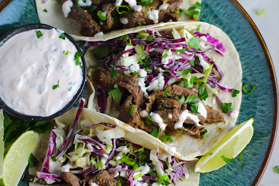 Korean Bulgogi Sauce Beef Tacos on a plate with flavorful Korean beef, crunchy Sesame Cabbage Slaw and a creamy, cool, Cilantro Lime Sriracha sauce!
