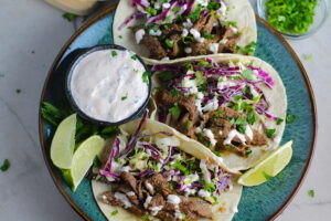 Korean Bulgogi Sauce Beef Tacos on a plate with flavorful Korean beef, crunchy Sesame Cabbage Slaw and a creamy, cool, Cilantro Lime Sriracha sauce!