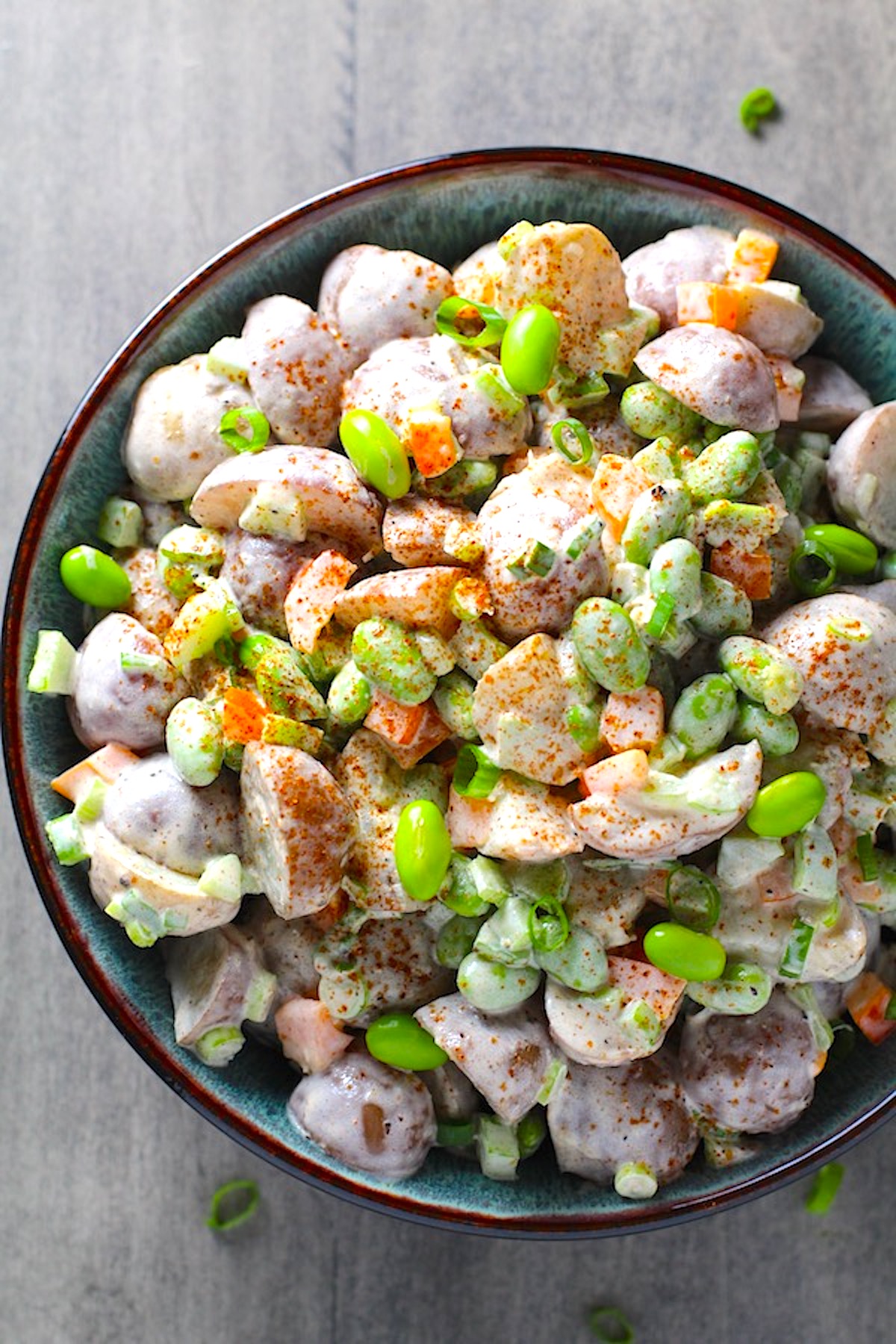Red Skin Potato Salad Recipe with Edamame and Harissa in a bowl on table. It's creamy, crunchy, meaty, and delicious.