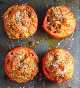 Stuffed Tomatoes on sheet pan on counter with chorizo, quinoa, parmesan cheese, chives, garlic, and oregano are simply divine!