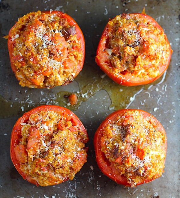 Stuffed Tomatoes on sheet pan on counter with chorizo, quinoa, parmesan cheese, chives, garlic, and oregano are simply divine!