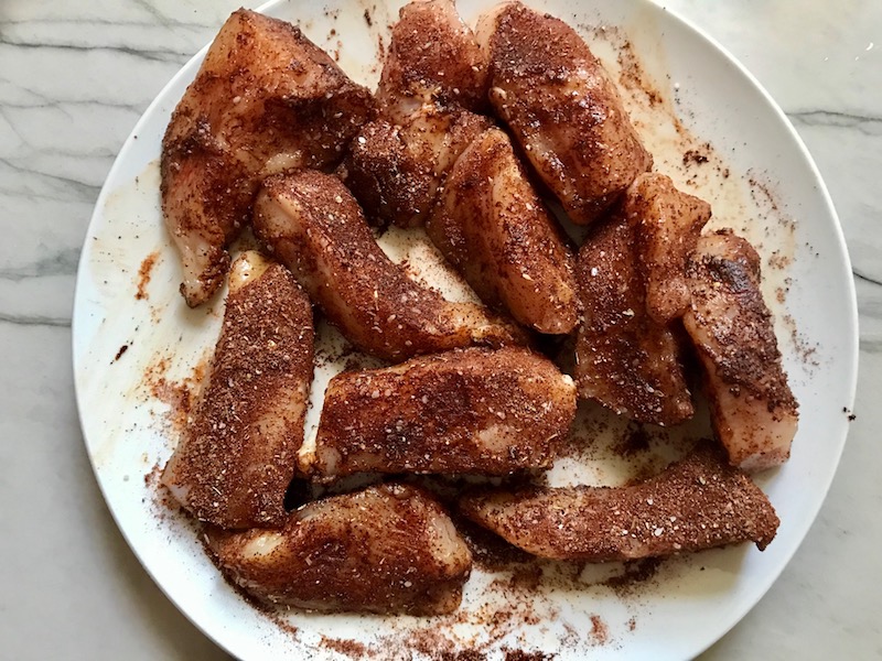 Raw chicken pieces coated in spice mixture for Creamy Corn and Blackened Chicken skillet dinner