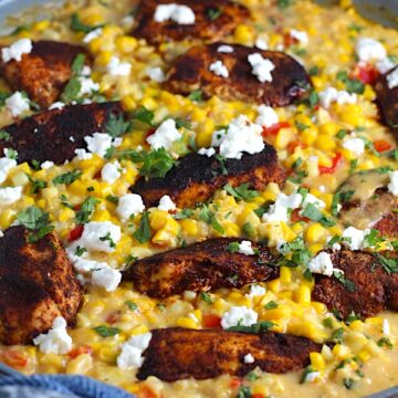 Creamy Corn and Blackened Chicken with feta and cilantro on top in a pan.
