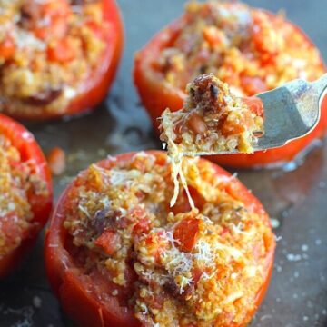 Stuffed Tomatoes on sheet pan on counter with chorizo, quinoa, parmesan cheese, chives, garlic, and oregano are simply divine! 