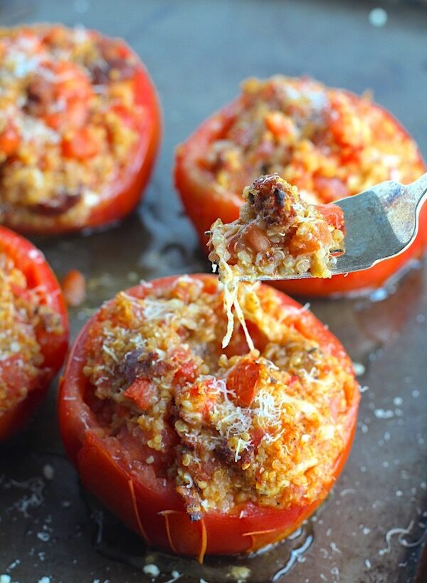 Stuffed Tomatoes on sheet pan on counter with chorizo, quinoa, parmesan cheese, chives, garlic, and oregano are simply divine!