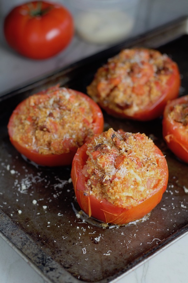 Stuffed Tomatoes on sheet pan on counter with chorizo, quinoa, parmesan cheese, chives, garlic, and oregano are simply divine!