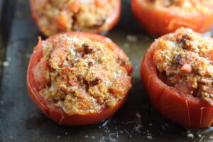 Stuffed Tomatoes on sheet pan on counter with chorizo, quinoa, parmesan cheese, chives, garlic, and oregano are simply divine!
