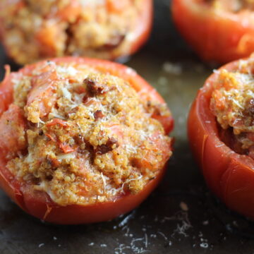 Stuffed Tomatoes on sheet pan on counter with chorizo, quinoa, parmesan cheese, chives, garlic, and oregano are simply divine!