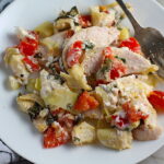 Chicken Artichoke Bake with Tomatoes and Goat Cheese on a plate with fork. It's a creamy, tangy, sweet, savory, mouth watering easy dinner that you can prep ahead!