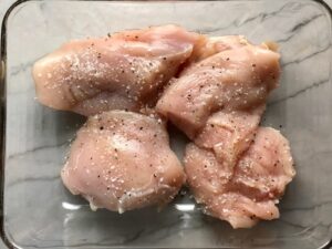 Cut raw chicken for Chicken Artichoke Bake with Tomatoes and Goat Cheese. It's a creamy, tangy, sweet, savory, mouth watering easy dinner that you can prep ahead!