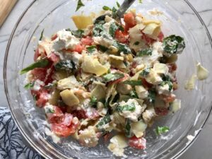 Ingredients in bowl for Chicken Artichoke Bake with Tomatoes and Goat Cheese. It's a creamy, tangy, sweet, savory, mouth watering easy dinner that you can prep ahead!