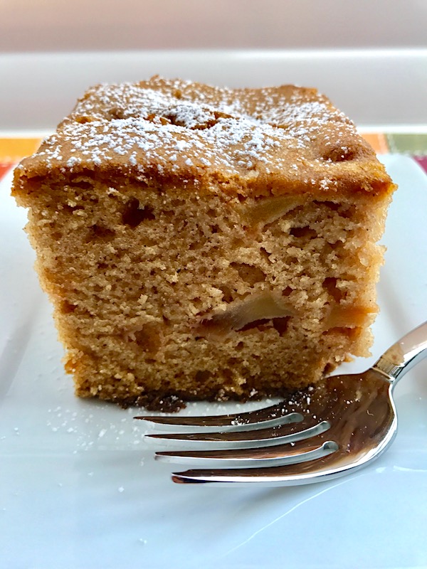 Slice of the Best Apple Cinnamon Cake on a plate with a fork. When you bake this cake, the entire house fills with the amazing aroma of cinnamon and apples. And then when you eat it, every bite gives you sweet cinnamon spice with a beautifully spongy texture and a sweet and tart pop from the apples.
