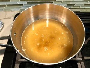 Garlic and Broth in pot for Broccoli Cheese Quinoa Bake It's a comfy cozy casserole that's perfect to make ahead for a simple weeknight side or main dish.