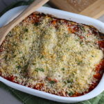 Chicken Parmesan Pasta Bake in casserole pan. It cooks entirely in one casserole dish, including the pasta! Shell pasta in flavorful, tangy tomato sauce is topped with zucchini, chicken, mozzarella, parm, and crunchy breadcrumb topping.