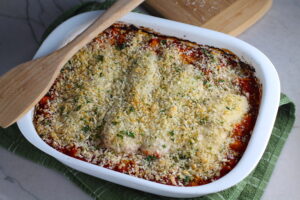 Chicken Parmesan Pasta Bake in casserole pan. It cooks entirely in one casserole dish, including the pasta! Shell pasta in flavorful, tangy tomato sauce is topped with zucchini, chicken, mozzarella, parm, and crunchy breadcrumb topping.