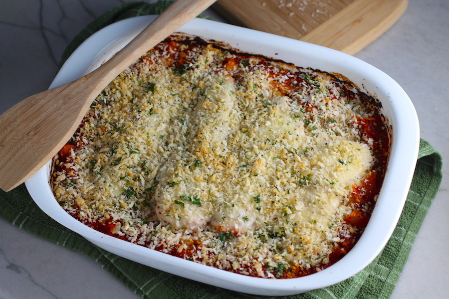 Chicken Parmesan Pasta Bake in casserole pan. It cooks entirely in one casserole dish, including the pasta! Shell pasta in flavorful, tangy tomato sauce is topped with zucchini, chicken, mozzarella, parm, and crunchy breadcrumb topping.