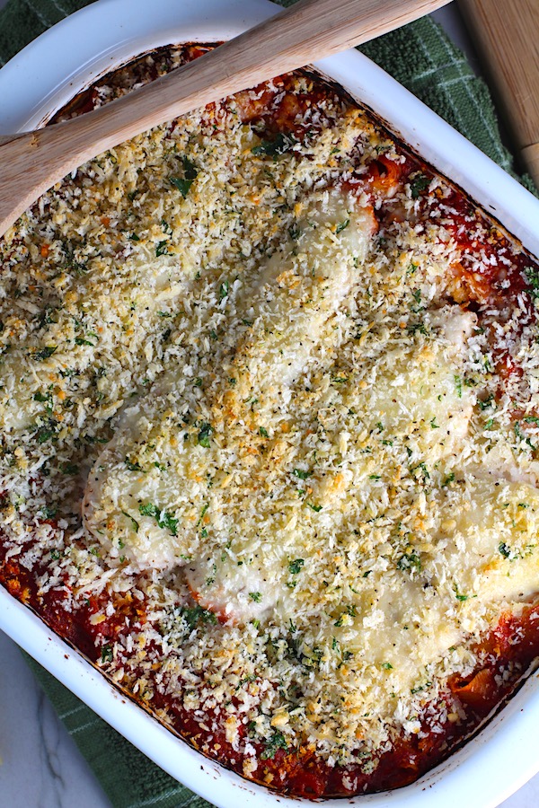Chicken Parmesan Pasta Bake in casserole pan. It cooks entirely in one casserole dish, including the pasta! Shell pasta in flavorful, tangy tomato sauce is topped with zucchini, chicken, mozzarella, parm, and crunchy breadcrumb topping.