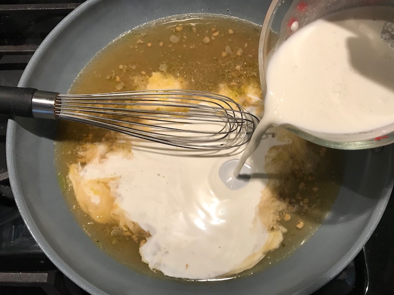 Pouring milk into pan with whisk Light and Easy Fettuccine Alfredo with Prosciutto