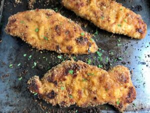 Oven Fried Chicken Breast on pan. The chicken is coated with Bacon Crumbs and Honey and it's healthier because it's baked, not fried, but still gives you all of the crispy, crunchy goodness! It also gives you sweet and salty crunch with the addition of honey and bacon!