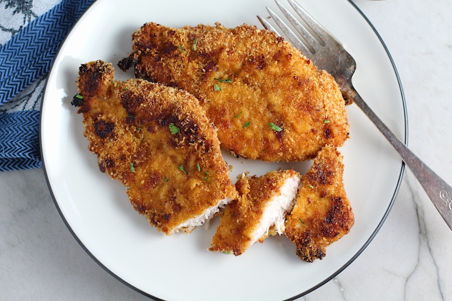 Oven Fried Chicken Breast cut on plate with fork. The chicken is coated with Bacon Crumbs and Honey and it's healthier because it's baked, not fried, but still gives you all of the crispy, crunchy goodness! It also gives you sweet and salty crunch with the addition of honey and bacon!