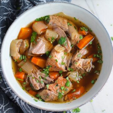 Paprika Pork Stew Recipe in a bowl with carrots, onion, parsley. It's an easy family dinner.