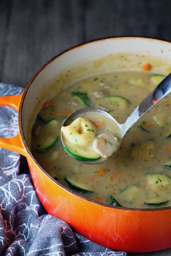 Creamy Chicken Sausage and Tortellini Soup in a large pot with ladle scooping. It's silky and creamy with onions, garlic, Chicken sausage, and zucchini bring so much flavor and texture. The tortellini give that delicious salty, creamy, hearty bite!