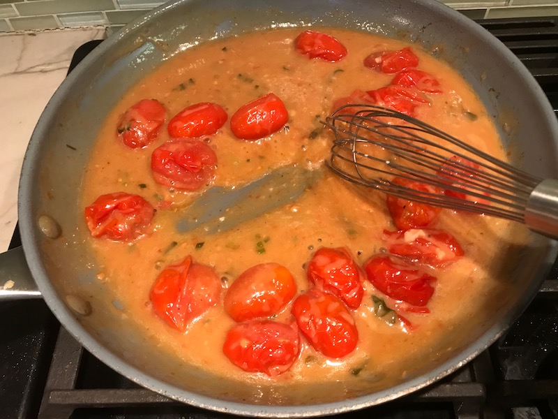 Bacon Tomato Sauce in pan for Smothered Chicken with Bacon, and Tomatoes. The chicken is smothered in a thickened sauce infused with smokey and salty bacon flavor. Cherry tomatoes give a sweet and tangy pop.