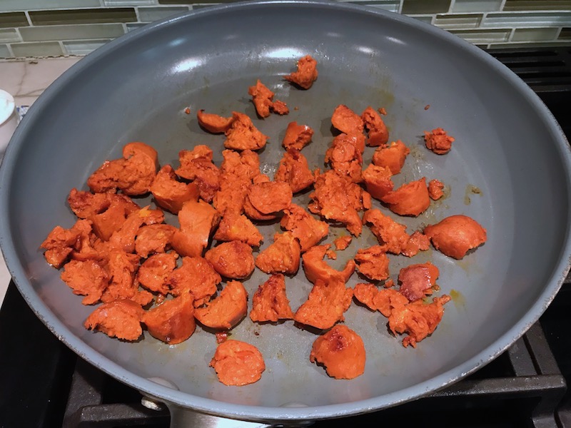 Chorizo pieces in frying pan for Creamy Green Beans and Mushrooms with Chorizo in a serving bowl are a creamy and savory side dish.