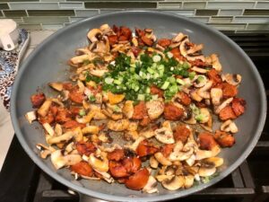 Chorizo, mushrooms, and scallions in frying pan for Creamy Green Beans and Mushrooms with Chorizo in a serving bowl are a creamy and savory side dish.