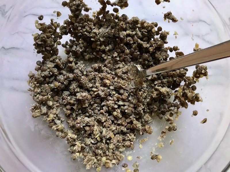 Fork mashing cooked lentils for Lentil and Zucchini Cakes. They have a crispy outside and soft inside and are perfect for an easy dinner! The flavors are simple but perfect with parmesan, oregano, scallions, lentils, and zucchini.