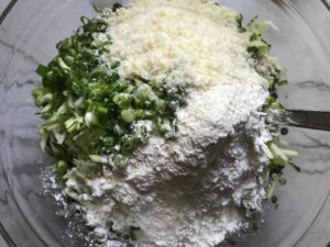 Parmesan, flour, shredded zucchini and lentils in a bowl for Lentil and Zucchini Cakes. They have a crispy outside and soft inside and are perfect for an easy dinner! The flavors are simple but perfect with parmesan, oregano, scallions, lentils, and zucchini.