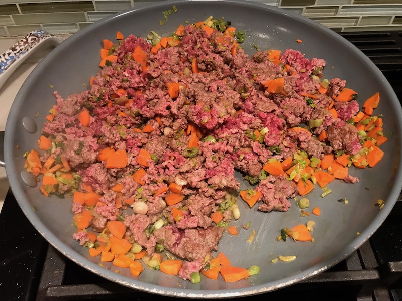 Carrots and raw beef mixture cooking in skillet for Empanada Beef Pie Recipe. It has a perfect flaky, buttery pastry on the outside with a savory, smokey, salty ground beef filling. The best part is that everything cooks in one skillet!
