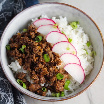 Korean Bulgogi Ground Beef and Rice Bowl with sliced radishes fanned out on top and scallion garnish.