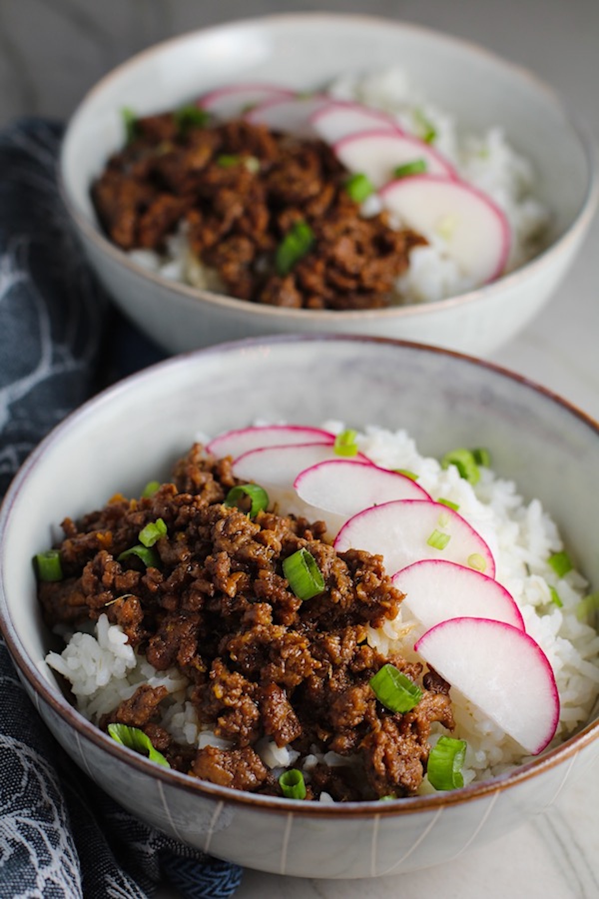 Korean Bulgogi Ground Beef and Rice Bowls with sliced radishes fanned out on top and scallion garnish.