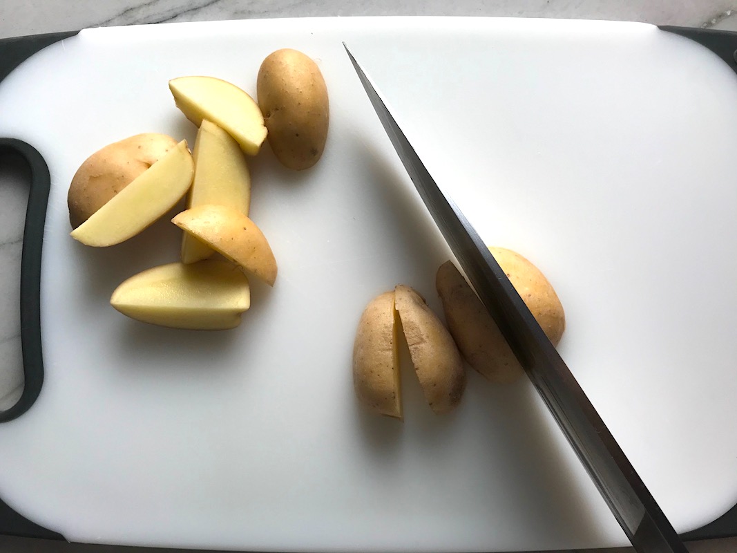 Knife slicing creamer potatoes for Garlic Potato and Steak Bites Recipe. It's an easy and delicious, one-pan family dinner! You get fantastic salty, buttery, tender steak and potatoes in each and every mouthwatering bite!