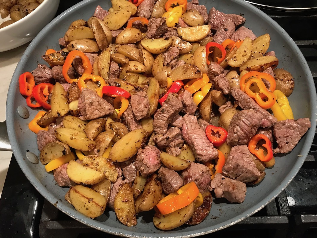 Garlic Potato and Steak Bites Recipe with sweet pepper slices in a pan on counter. It's an easy and delicious, one-pan family dinner! You get fantastic salty, buttery, tender steak and potatoes in each and every mouthwatering bite!