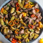 Garlic Potato and Steak Bites Recipe with sweet pepper slices in a pan on counter. It's an easy and delicious, one-pan family dinner!  You get fantastic salty, buttery, tender steak and potatoes in each and every mouthwatering bite! 