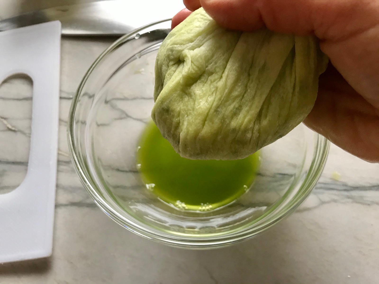 Hand squeezing liquid out of towel with zucchini for Healthy Meatballs with Zucchini & Lean Beef. They're loaded with flavor from the garlic, minced onion, salt, and pepper. The zucchini brings moisture, texture, and bulks up the meatballs with healthiness.