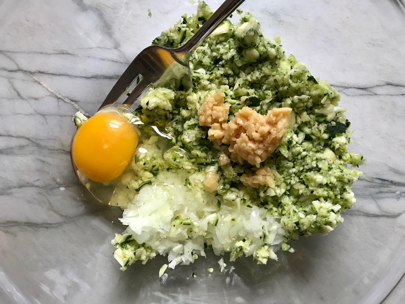 Ingredients in bowl for Healthy Meatballs with Zucchini & Lean Beef. They're loaded with flavor from the garlic, minced onion, salt, and pepper. The zucchini brings moisture, texture, and bulks up the meatballs with healthiness.